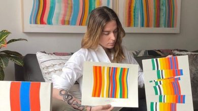 image of visual artist Amber Vittoria showing two of her physical artworks to the camera