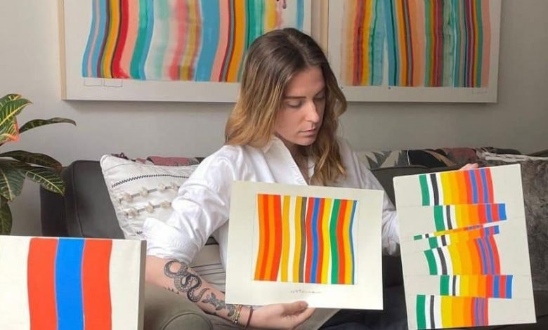 image of visual artist Amber Vittoria showing two of her physical artworks to the camera