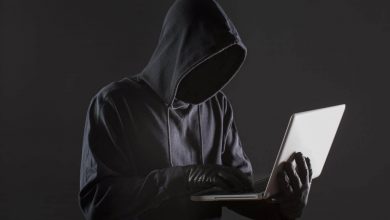 image of an anonymous hacker holding a laptop