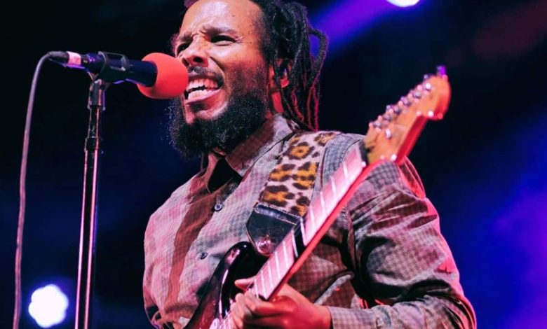 image of reggae musician Ziggy Marley performing guitar and singing during a live concert